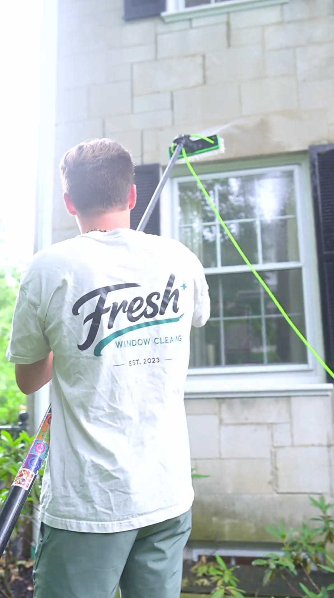 Fresh Windows technician cleaning residential windows with the branded shirt